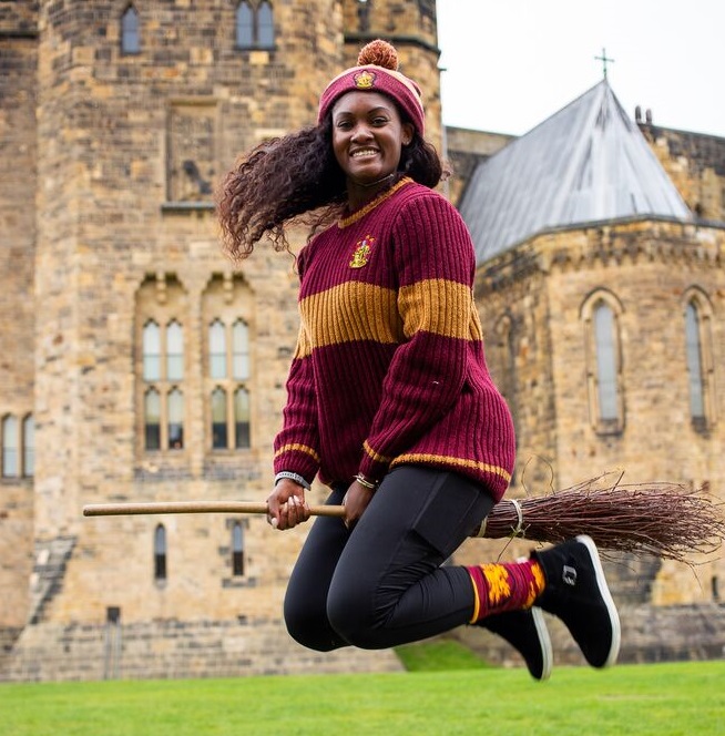 Girl with Gryffindor clothes on, riding a broomstick