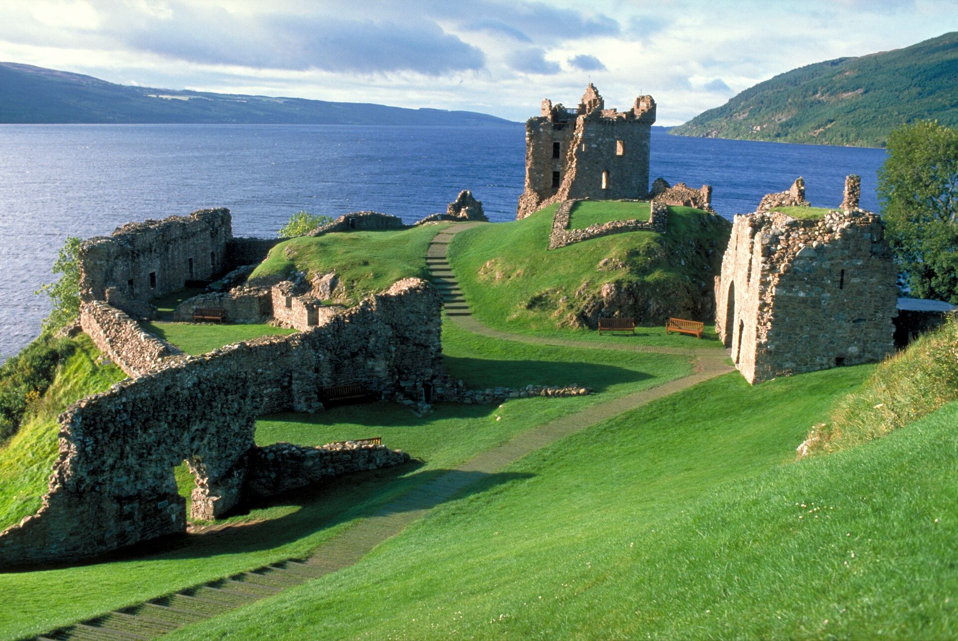 Urquhart Castle with Loch Ness in the background, surrounded by lush greenery