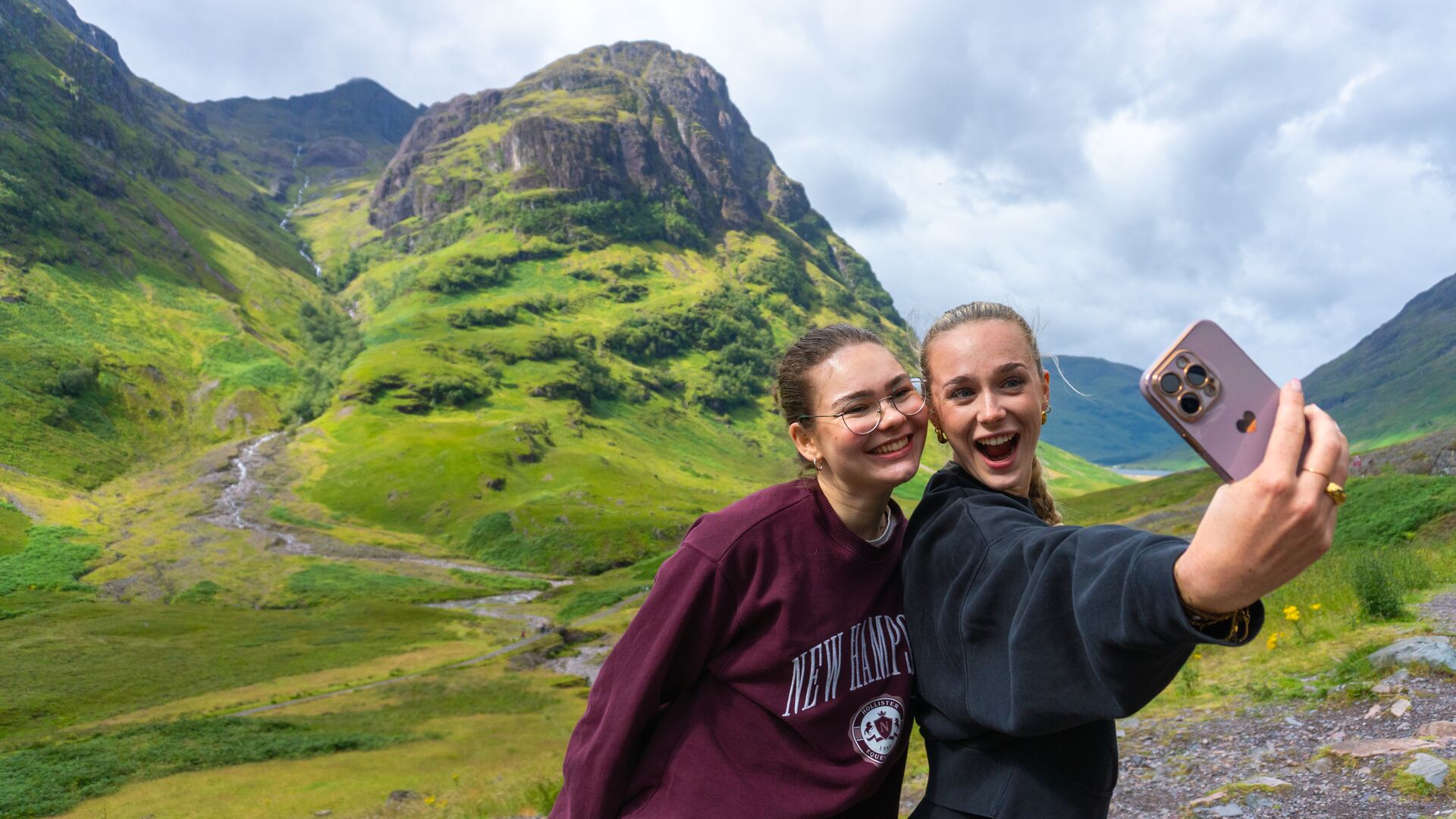 Two friends taking a selfie with the dramatic Glen Coe landscape in the background